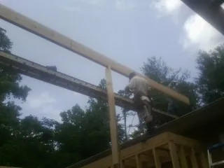 Carpenter setting a ridge beam over a new addition frame — Ice Dam Removal by Roofing Brothers in Greenvale