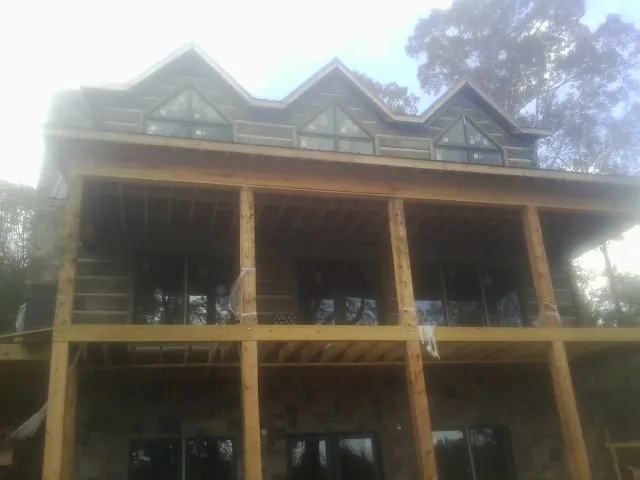 Dormers and porch framing on a large log home under construction — Roof Coating work by our crew in Greenvale