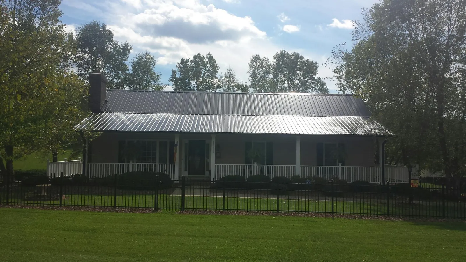 Gray metal roof on a brick ranch with a full width front porch — Gutter Guard Installation work by our crew in Greenvale