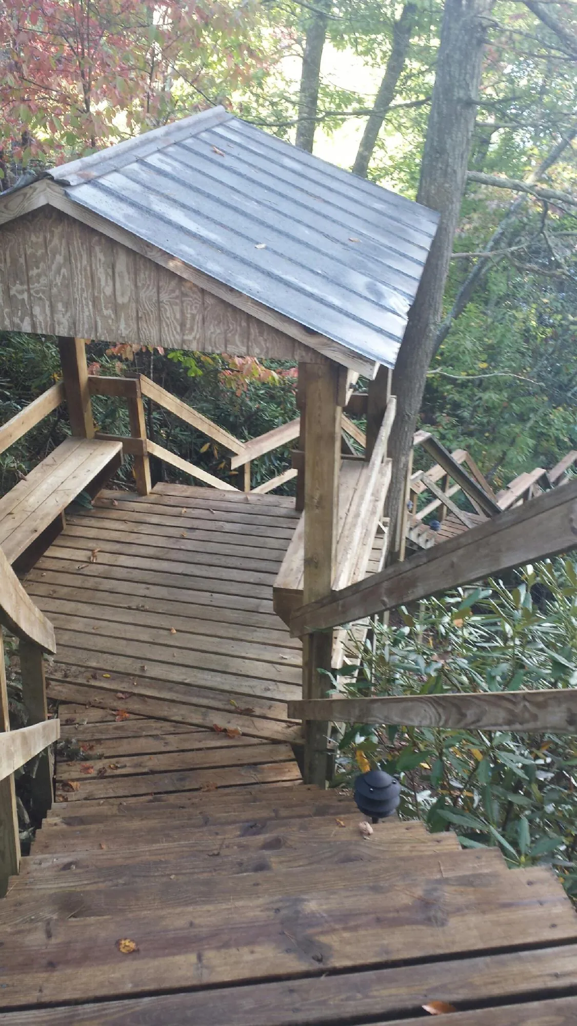 Metal roofed shelter over wooden steps on a wooded walkway — Skylight Repair & Installation work by our crew in Greenvale