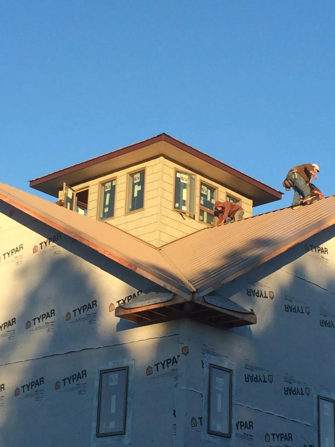Roofers working around a rooftop cupola on a new metal roof at sunset — Roof Waterproofing in Greenvale by Roofing Brothers